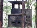 Wieżyczka strażnicza przy bocznicy kolejowej z jedynym zchowanym fragmentem betonowego płotu, który otaczał obóz